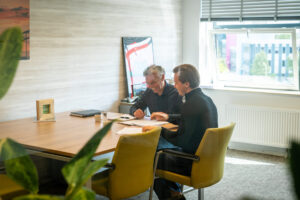 twee medewerkers van Q accountants en belastingadviseurs aan een tafel op kantoor.